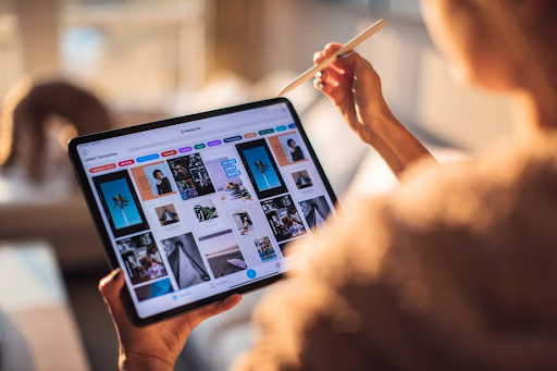 Photograph of a person engrossed in their iPad, exploring the visual world of Pinterest. The individual is seen holding the iPad, fingers swiping and scrolling through the app's interface. Their focused expression and the device's screen illumination highlight the immersive experience of discovering inspiration, ideas, and creative content on Pinterest, known for its vast collection of images, designs, and user-generated content.